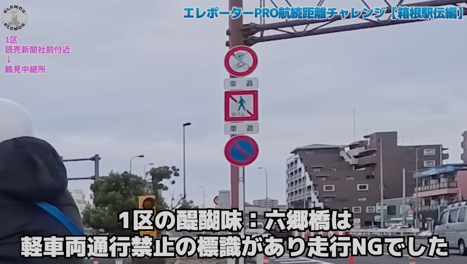 2026-05-04_162941 | ELEMOs Video thumbnail of a Japanese street with a signpost showing bicycle prohibition, a person in a hooded jacket in the foreground.