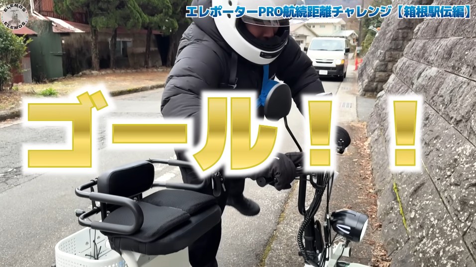 2026-05-04_182351 | ELEMOs Person in a helmet riding an e-bike on a street, with large yellow text ゴール! ('Goal!') across the frame, celebrating a finish.