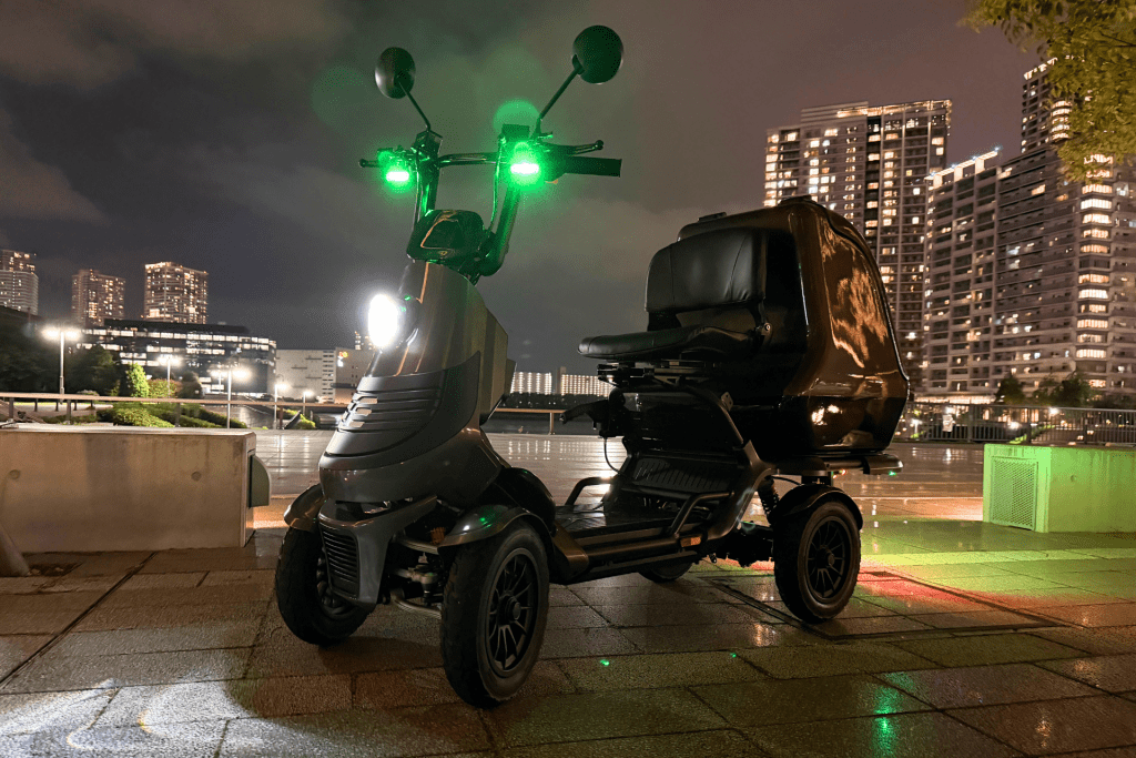 Three-wheeled urban scooter with bright green lights, parked on a wet rooftop at night with a city skyline in the background.