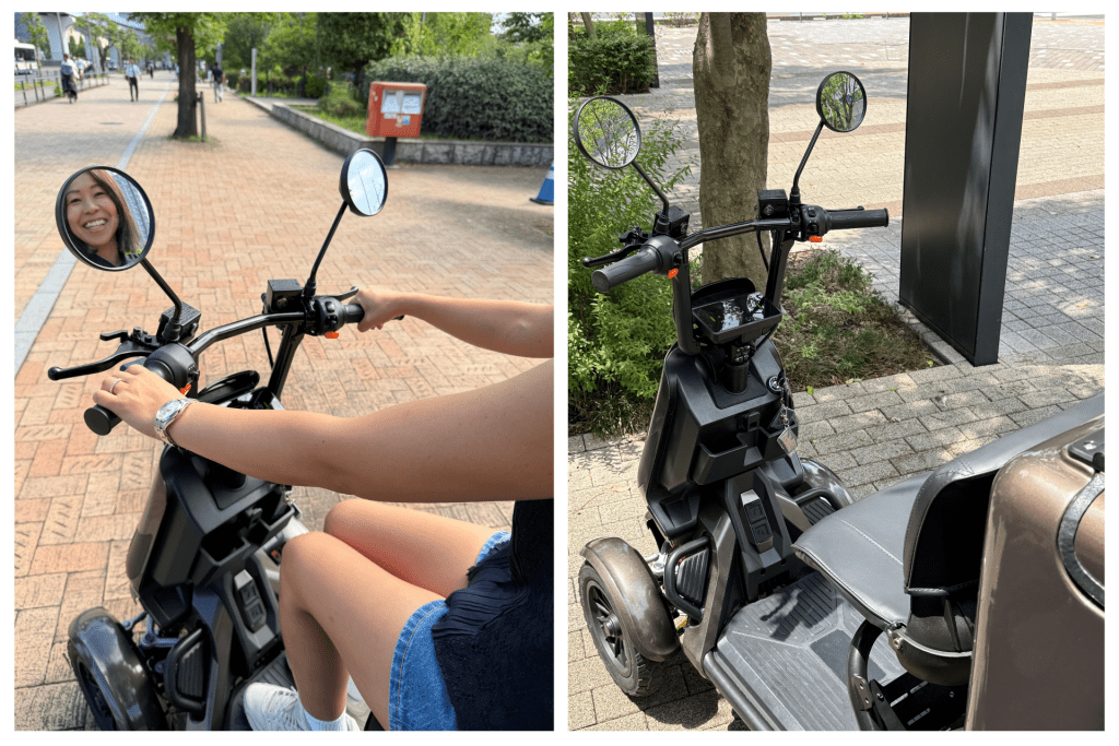 Smiling rider on a scooter seen from the left, with the rear-view mirror showing her face as the brick-paved path and pedestrians stretch into the distance.