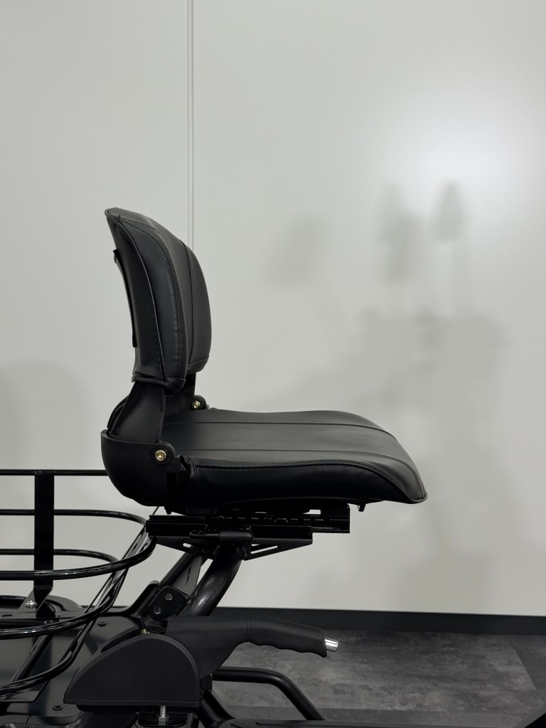 Black leather office chair seat and backrest mounted on a metal frame against a plain light wall.
