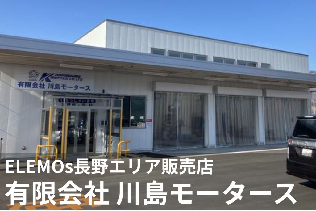 Exterior view of Kawashima Motors Co., Ltd. storefront with blue Japanese signage and a white building facade; a parked dark SUV is visible on the right.