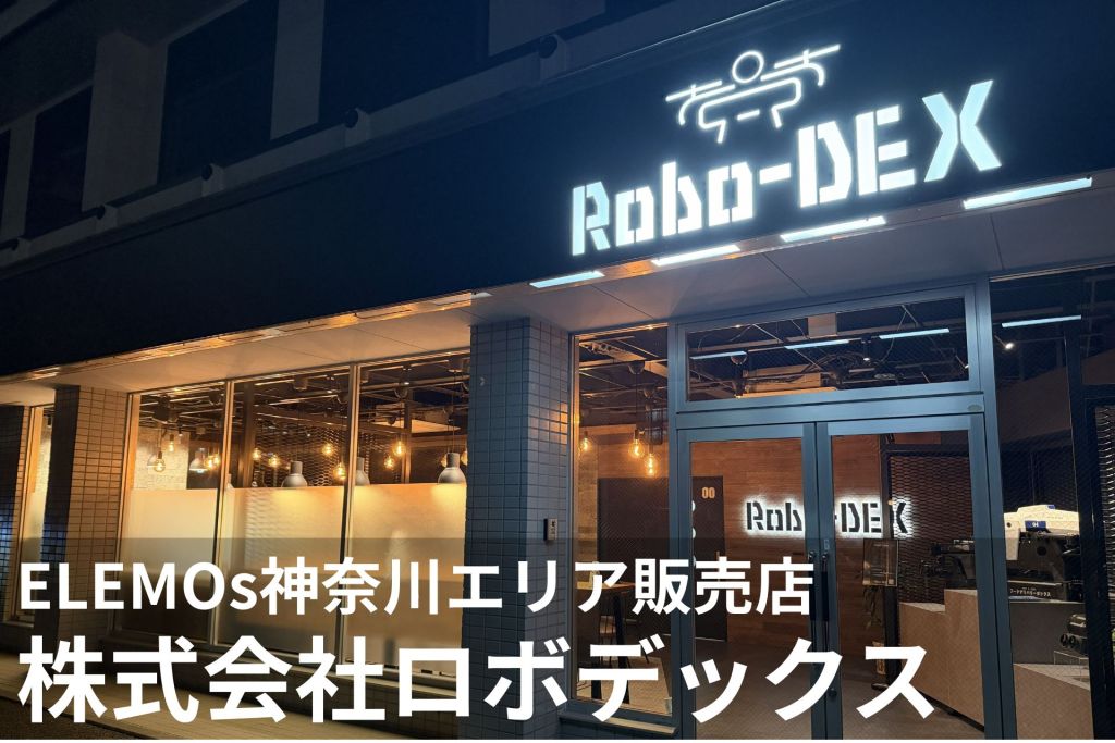 Storefront at night with a bright Roboto-DEX sign and warm interior lights visible through glass doors and windows; a tech store exterior.