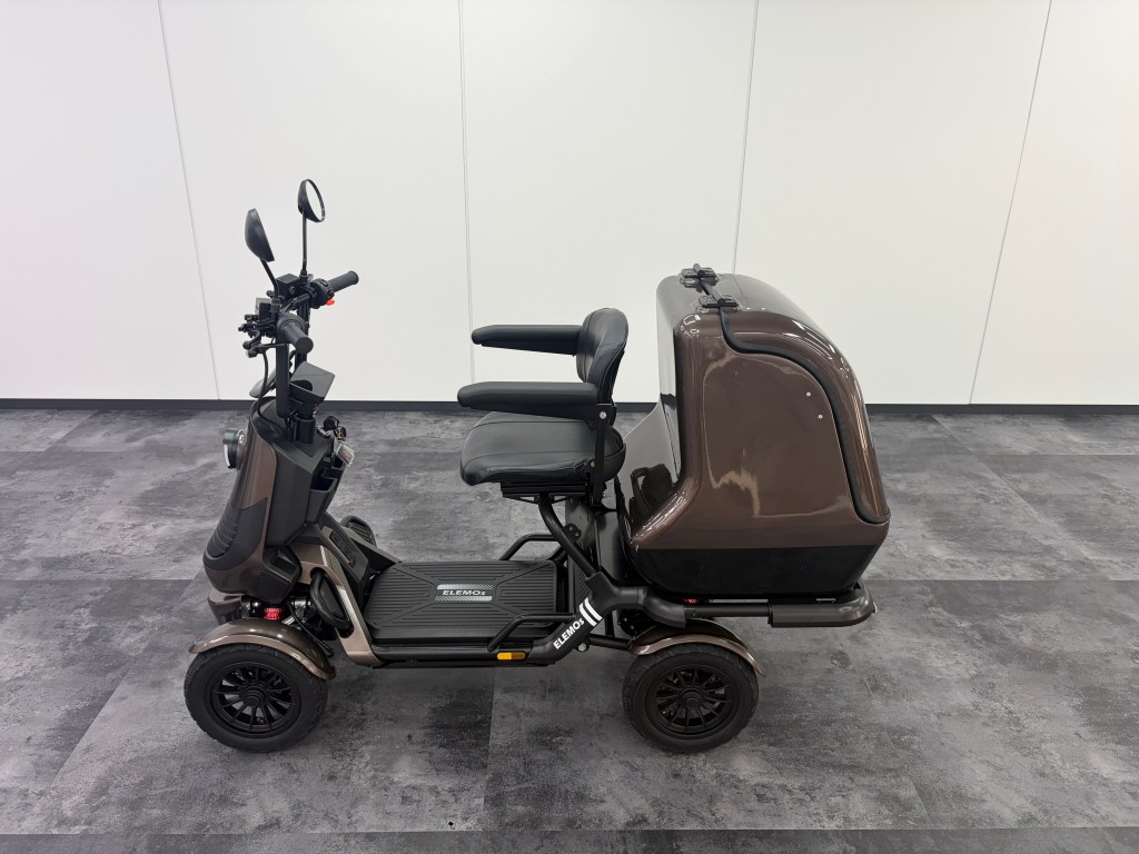 ELEGRAN G-class PREMIUM エレグラン ジークラス プレミアムサイドビュー | ELEMOs Electric mobility scooter with brown housing, black seat, and handlebars in a showroom.