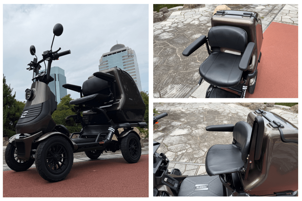 ELEGRAN PREMIUM① | ELEMOs Brown three-wheeled mobility scooter parked on red pavement, showing handlebars, seat, and footboard with'ELEMOS' branding; urban buildings in background (informative product photo).