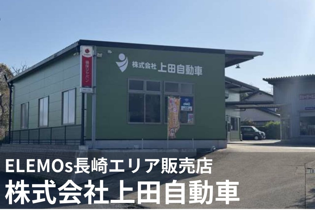 Exterior view of a green company building with a white logo and Japanese sign 株式会社上田自動車, a red vertical banner, large windows, and a parked car nearby.