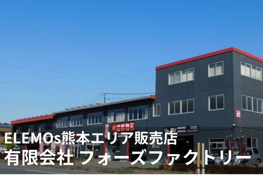 Dark gray multi-story commercial building with red roof trim under a blue sky; large white Japanese text overlays the lower portion of the image (storefront signage).